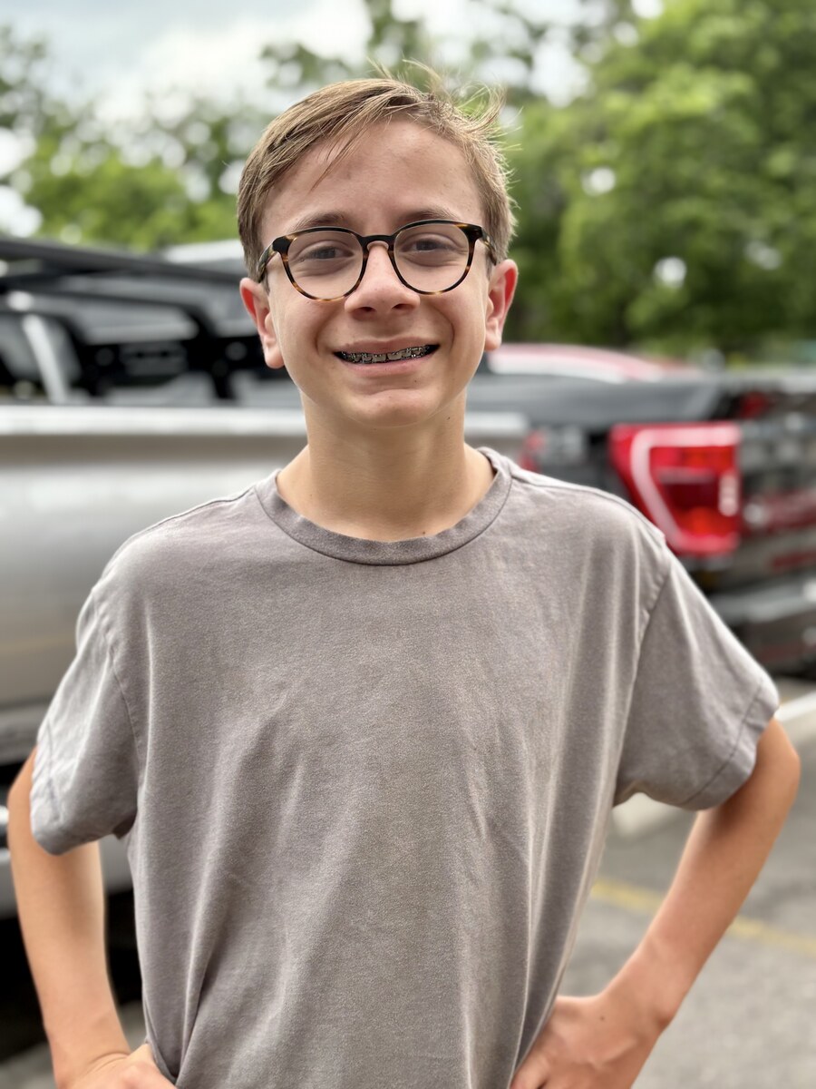 Quinn, smiling in front of a parked truck